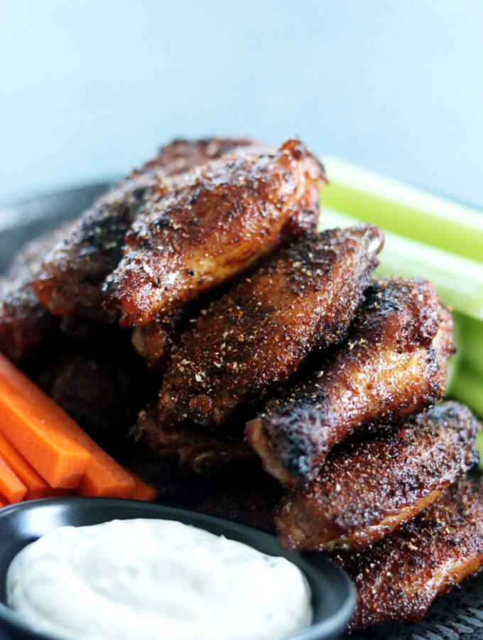 A plate of smoked chicken wings with celery, carrots, and bleu cheese dressing.